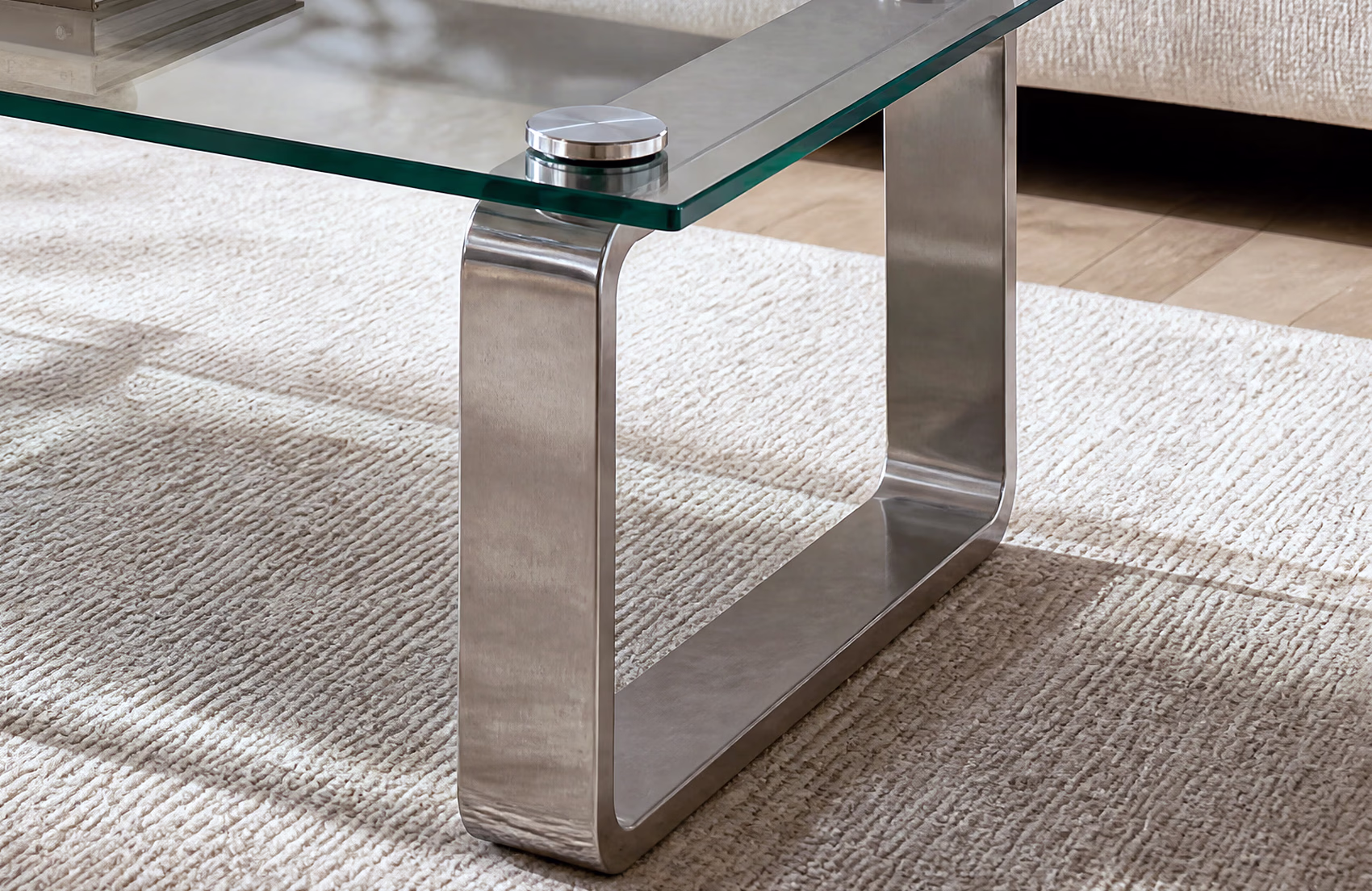 The same glass edge and chrome disc in the finished room scene, the rug visible through the glass.